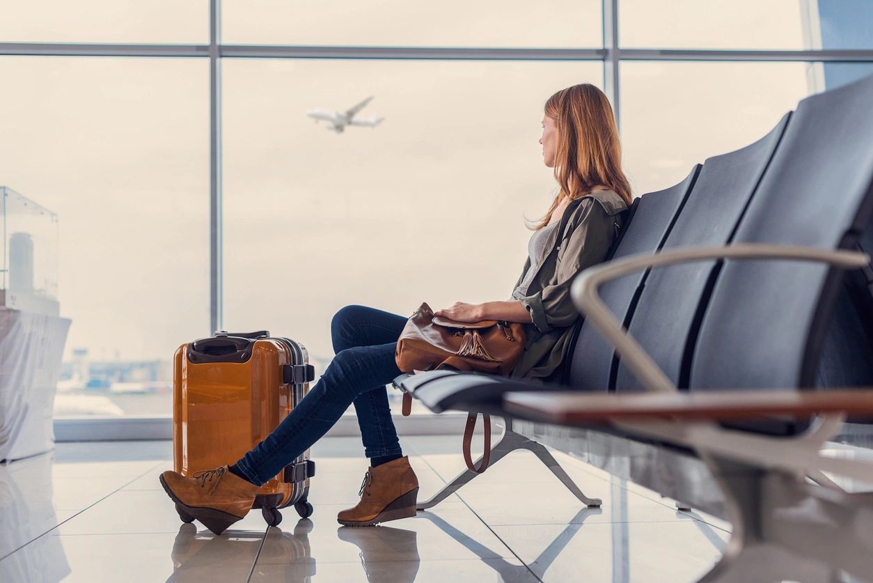 A woman sitting at the airport with her baggage